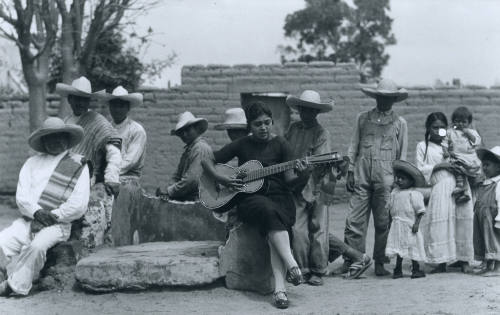 Mujer tocando la guitarra con un grupo de campesinos. Impresión de negativo donado por Vittorio Vidali. Fototeca INAH.